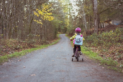 girl riding bike using training wheel stabilisers